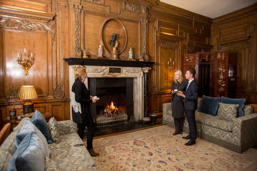 people standing around a fireplace and enjoying Leeds Castle of corporate packages 