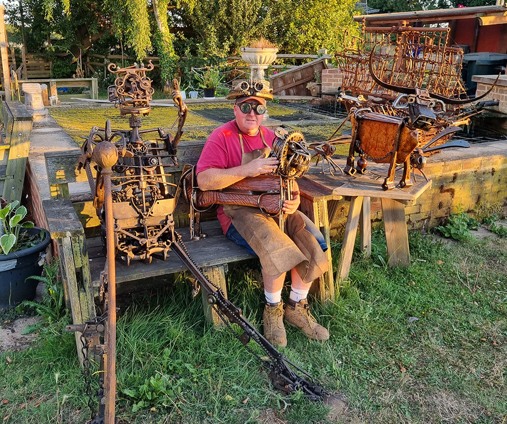 Rob Packman sitting down on a bench with his sculptures